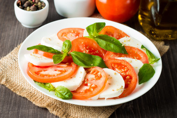 Close-up photo of caprese salad with ripe tomatoes, basil, buffalo mozzarella cheese. Italian and Mediterranean food concept. Fresh and healthy organic meal. Starter and antipasti. 