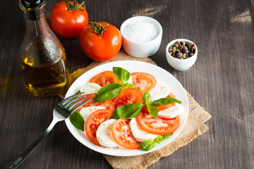 Close-up photo of caprese salad with ripe tomatoes, basil, buffalo mozzarella cheese. Italian and Mediterranean food concept. Fresh and healthy organic meal. Starter and antipasti. 