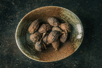 Black cardamom on a bowl with rustic background