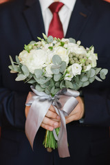 Groom holding wedding bouquet. Crop on bouquet