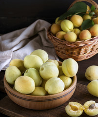 ripe apricots in a wooden bowl on a brown table