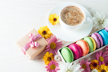 Photo of cake macarons, gift box, tea, coffee, cappuccino and flowers. Sweet romantic food macaroon concept. Morning breakfast and presents. Valentine's day concept.
