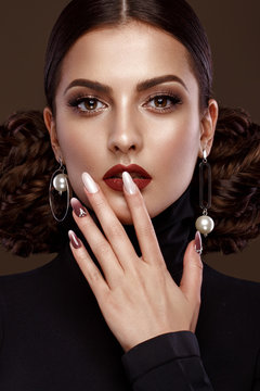 Pretty girl with unusual hairstyle, bright makeup, red lips and manicure design. Beauty face. Art nails. Studio portrait