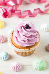 Closeup of cupcakes with vanilla, berries, pink and white cream, chocolate and sprinkles on wooden background. Selective focus. Sweet dessert tasty food concept muffin.