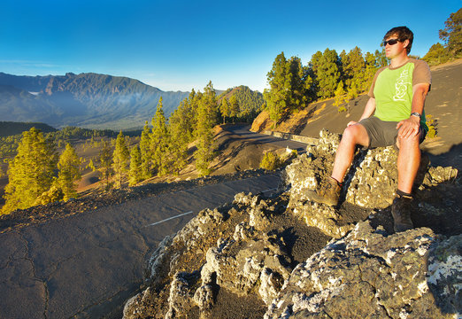 Man sitting next to the road watching a landscape, island of La Palma, Canary Islands, Spain
