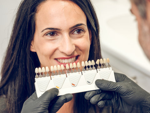 Smiling woman and dentist choosing denture