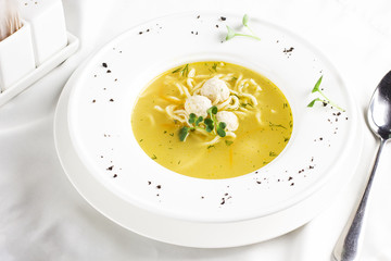 Chicken soup with meatballs and noodles in white table