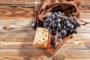 Red wine, cheese and red grapes on a wooden background. Top view