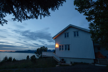 White house on the shore of lake with view to sunset in the Norway at summer