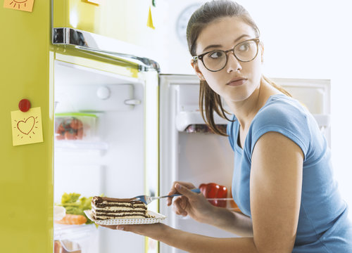 Hungry woman taking a dessert from the fridge