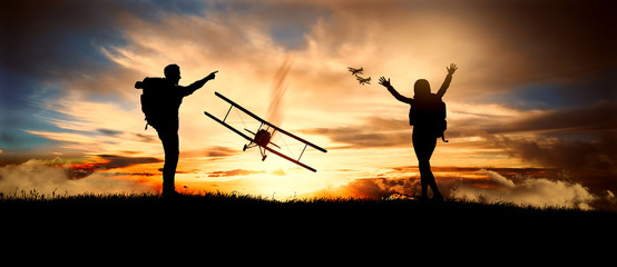 couple looks at old biplanes fly at sunset © ginettigino