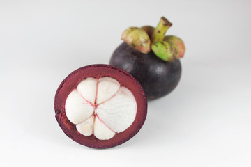 Isolated tropical fruits. One whole mangosteen and another cut in half isolated on white with clipping path