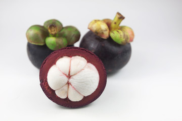 Isolated mangosteens. Two whole fruits and one half isolated on white background with clipping path