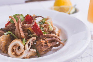 Greek Fried Squids Calamari with Red Chili Pepper and Fresh Mint Leaves on White Plate