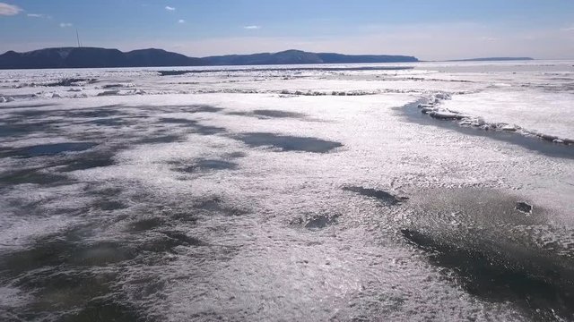Aerial view of the great river with floating ice floes during sundown. Drifting of ice. Driving of ice. Ice floe.