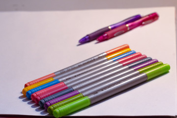 A variety of colored markers against white paper 