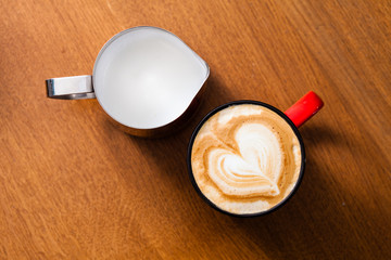 Red cup of latte art coffee on wood table