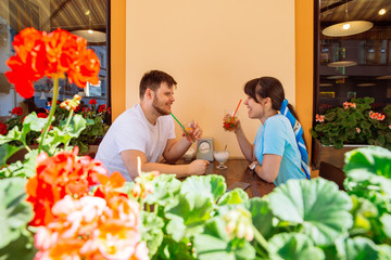 Naklejka premium couple sitting in summer cafe drinking cool drinks and talking