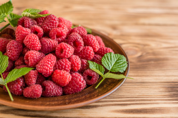 Tasty juicy sweet raspberry on a wooden background. It can be used as a background