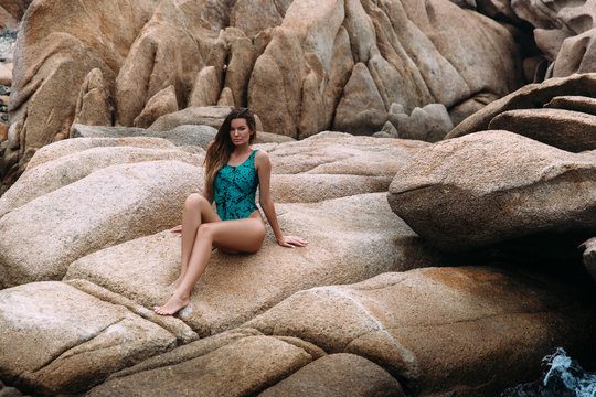 Sexy slim model with long legs sunbathing on a large flat stone on the beach, sunbathing.