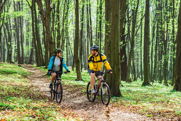 Fototapeta premium couple riding bicycle in forest in warm day
