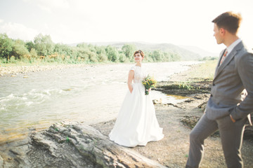 Fototapeta na wymiar Bride and groom holding beautiful wedding bouquet. Posing near river