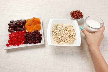 The girl took milk to pour it into oatmeal. Useful and healthy breakfast. White background