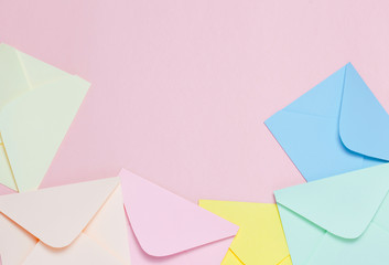 Frame from colorful envelopes on pink table top view.