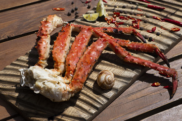 Fresh crab claws with sauce, pepper and lemon on vintage wooden background. 
