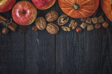Wooden background with pumpkin, apples, nuts and spices.