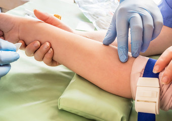 Nurse taking blood sample from a vein of a child