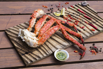 Fresh crab claws with sauce, pepper and lemon on vintage wooden background. 

