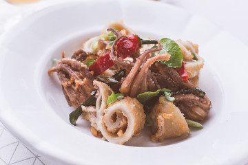 Greek Fried Squids Calamari with Red Chili Pepper and Fresh Mint Leaves on White Plate