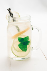Fresh Mojito Cocktail with Cold Ice, Lemon and Mint Leaves in Mason Jar on White Wooden Background as Bright Summer Concept