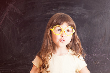 Happy little girl schoolgirl from the blackboard