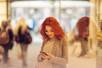 Beautiful young woman in the city, mall is busy with her mobile phone, talking, smiling
