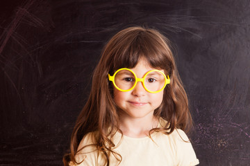 Happy little girl schoolgirl from the blackboard