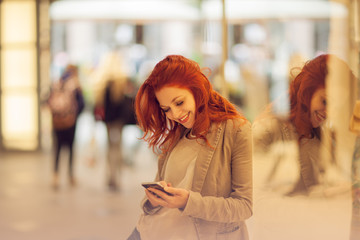 Beautiful young woman in the city, mall is busy with her mobile phone, talking, smiling