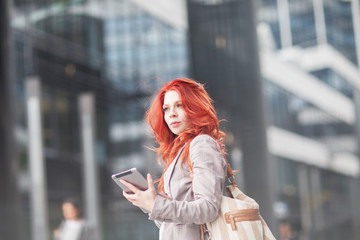 young beautiful business woman holding tablet, working in downtown, outdoors 