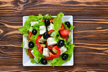 Greek salad on a wooden background. Space for text or design.
