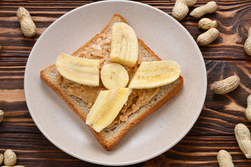 Peanut butter toast with banana slices  on wooden background