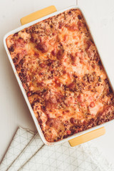 Lasagna Bolognese with Beef, Tomato Sauce and Green Basil on Rustic White Wooden Table