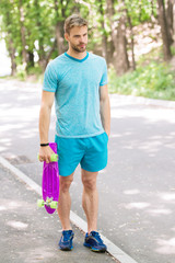 Still childish. Guy carries penny board, ready to ride. Man calm face carries penny board park...