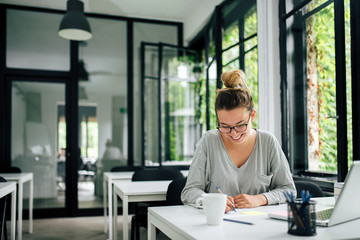 Fototapeta premium Young woman writing a note.