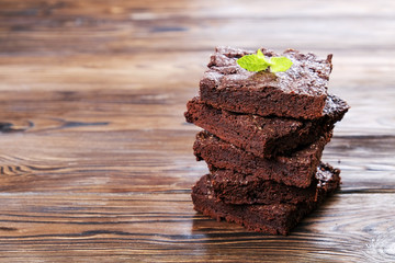 Stack of square pieces of homemade brownies with dark chocolate spread paste on wood texture table....