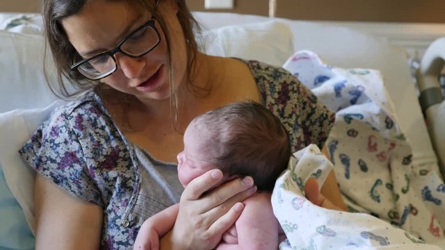 Tired mother burping her newborn girl after nursing her in the hospital