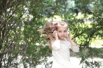 Small child enjoy music in headphones outdoor. Kid dancer with long flying hair. Melody sound and mp3. Girl dance to music in summer park. Summer fun and joy