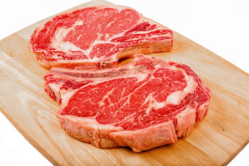 Raw rib steaks on a cutting board.