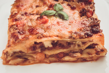 Homemade Lasagna with Minced Beef, Tomato Sauce and Fresh Basil on White Plate