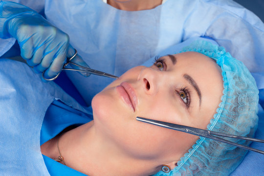 hands of cosmetologist preparing for lip surgery holding tools near in female mouth